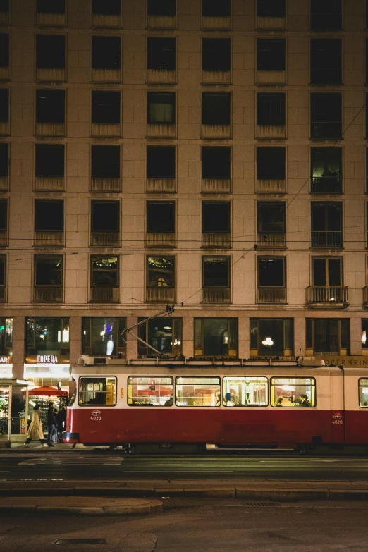 there is a red tram that is going by the building