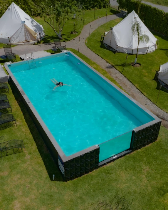 an above view of an empty pool surrounded by white tents