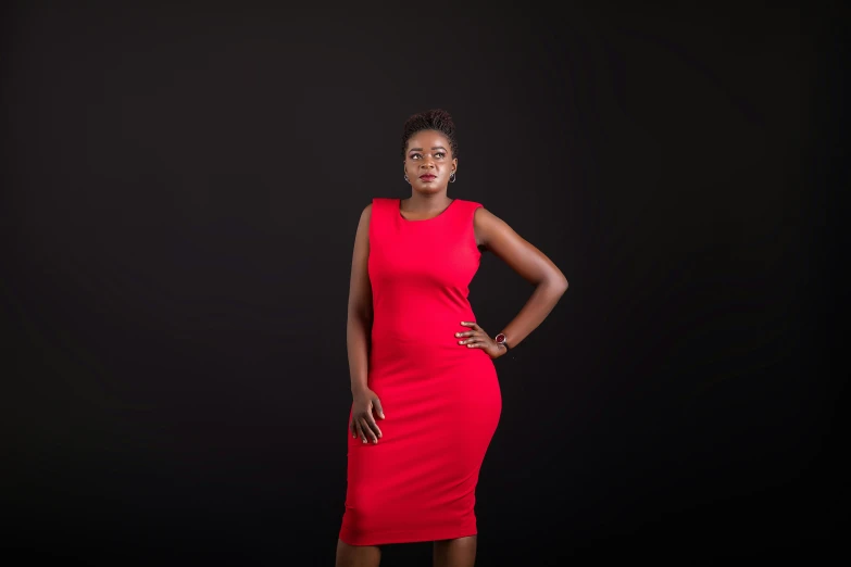 a woman standing on a black background wearing a red dress