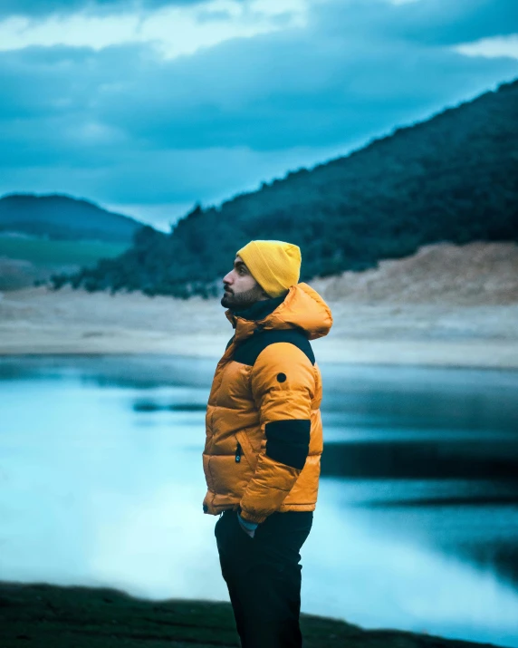 a man standing with his head turned away in front of some water