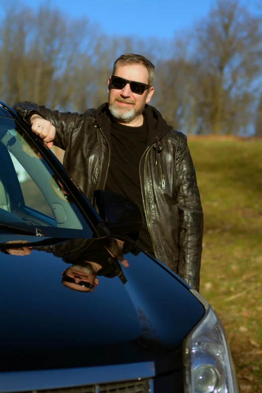 a man in sunglasses standing next to his car