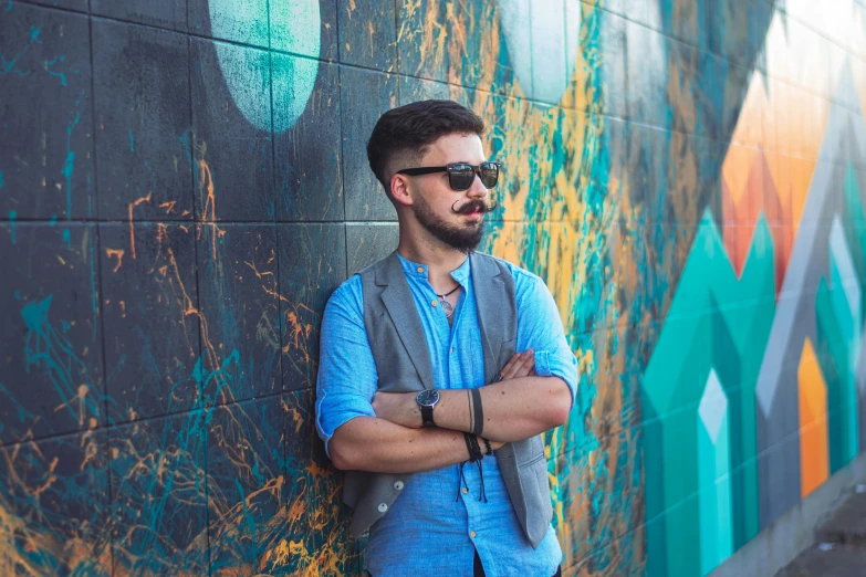 a man in blue shirt standing in front of graffiti covered wall