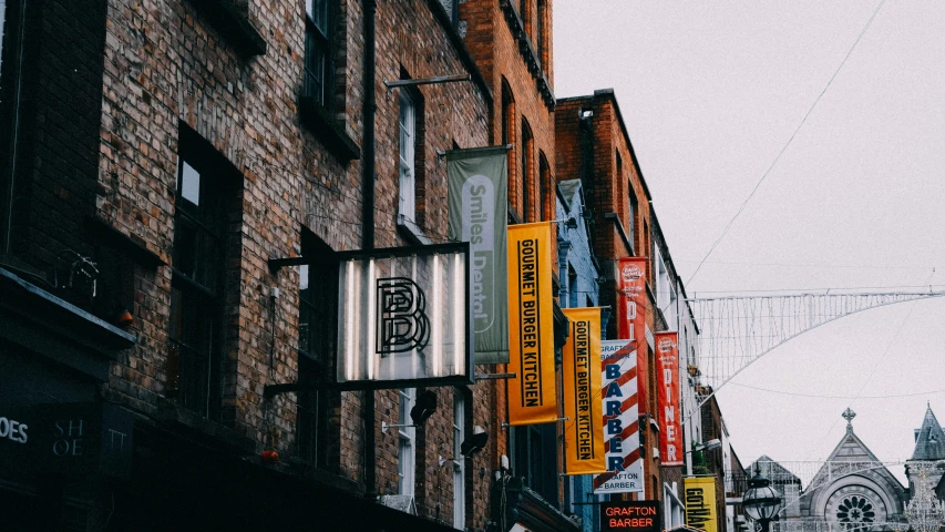 the front of a tall brick building with several hanging signs