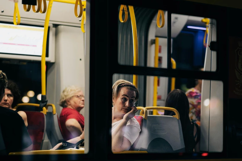 a woman sitting down on the bus with an umbrella and cellphone