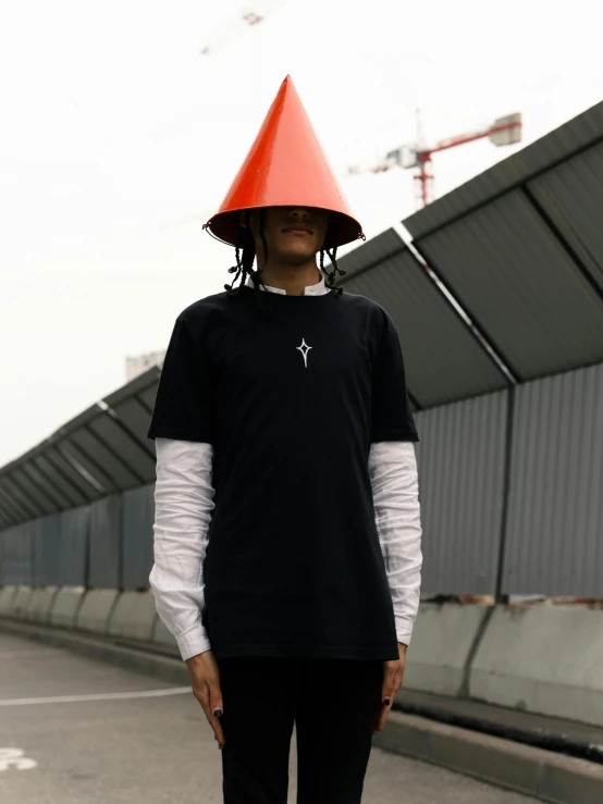 an individual is standing in the street and wearing a strange hat