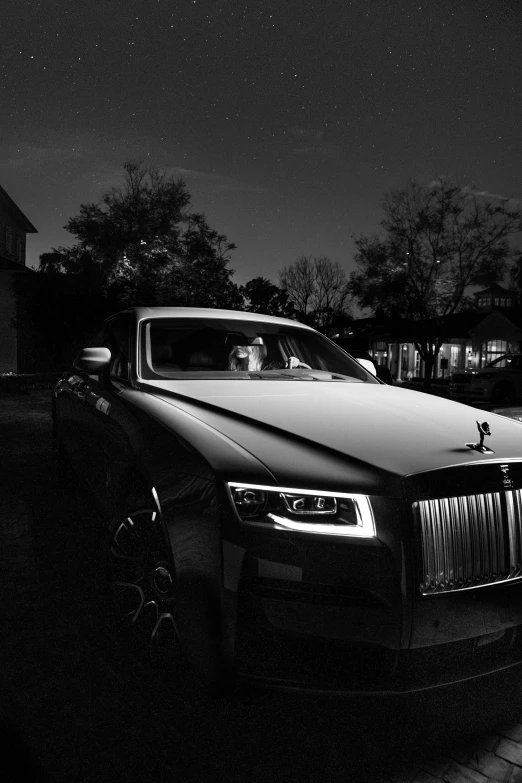 a rolls royce parked in a driveway at night