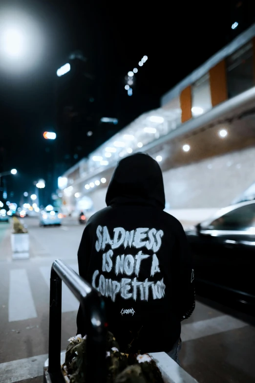 a person with black hoodie on sitting next to a car