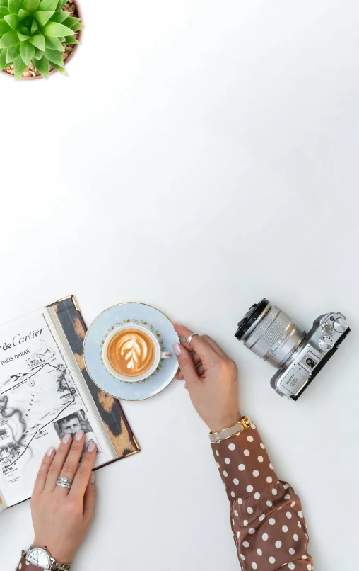 two hands with coffee, camera and book