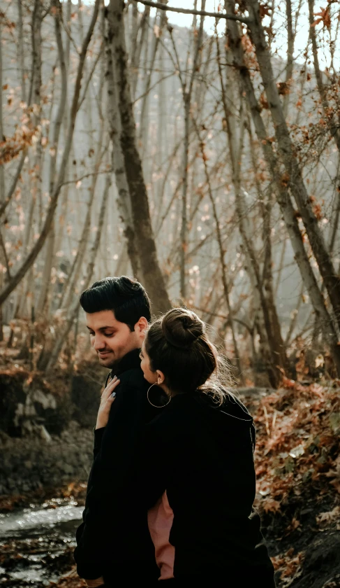 a couple stands by the river for their engagement pos