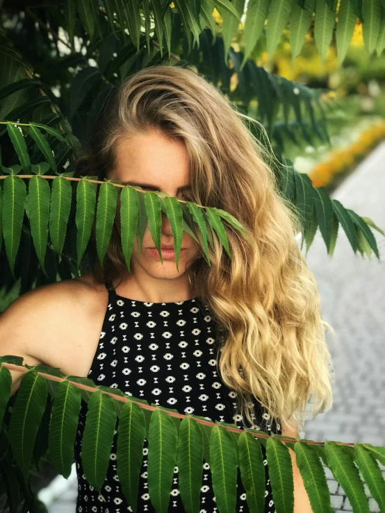 a woman standing behind some leaves in a park