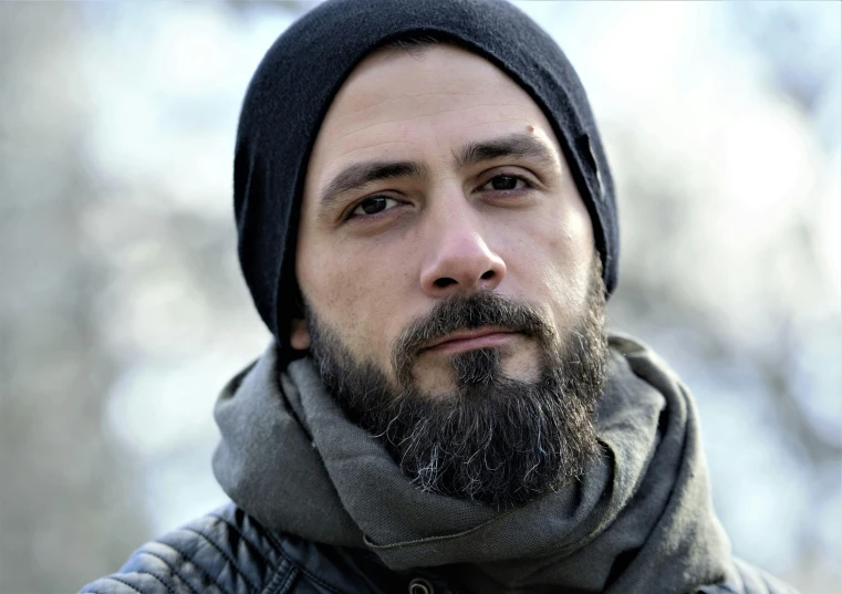 a bearded man with a gray scarf and a beanie