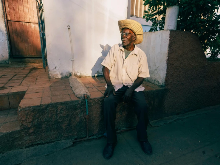 a man sits outside his house on a street