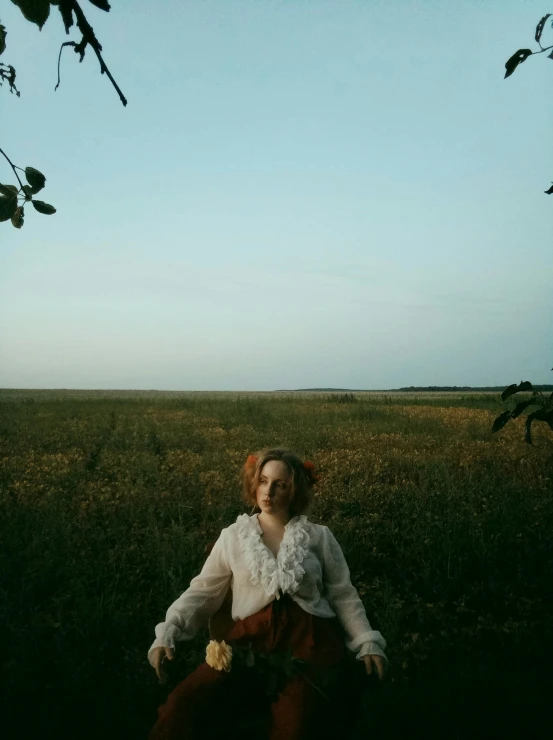 a woman wearing red pants is sitting in a field