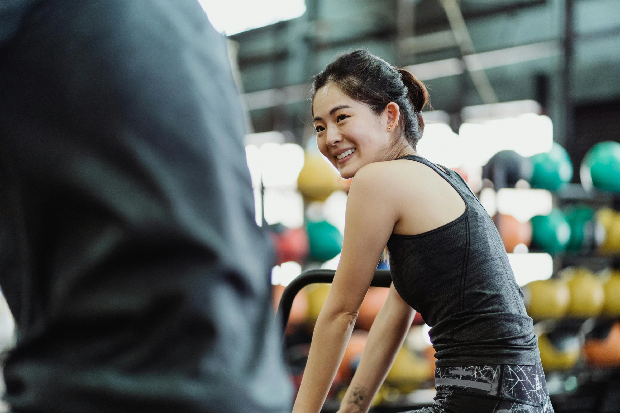 young woman smiling and sitting on exercise bike in a gym