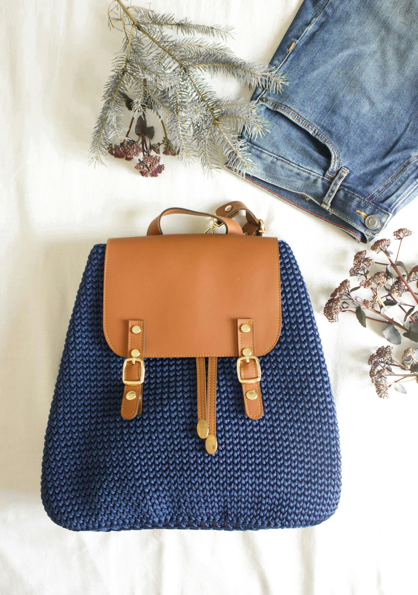 a bag next to jeans and flower bouquet