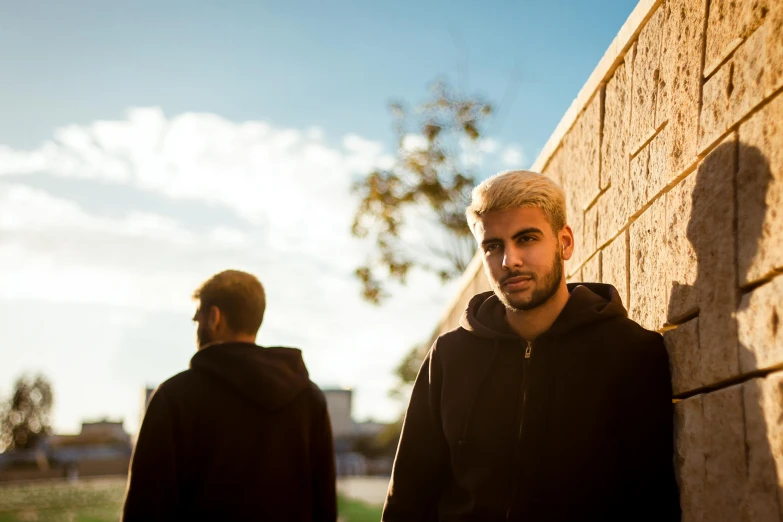 two men with grey hair are standing next to a brick wall