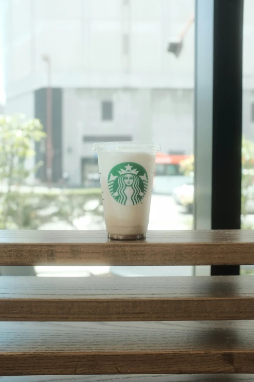 a starbucks drink sits on top of a wooden bench