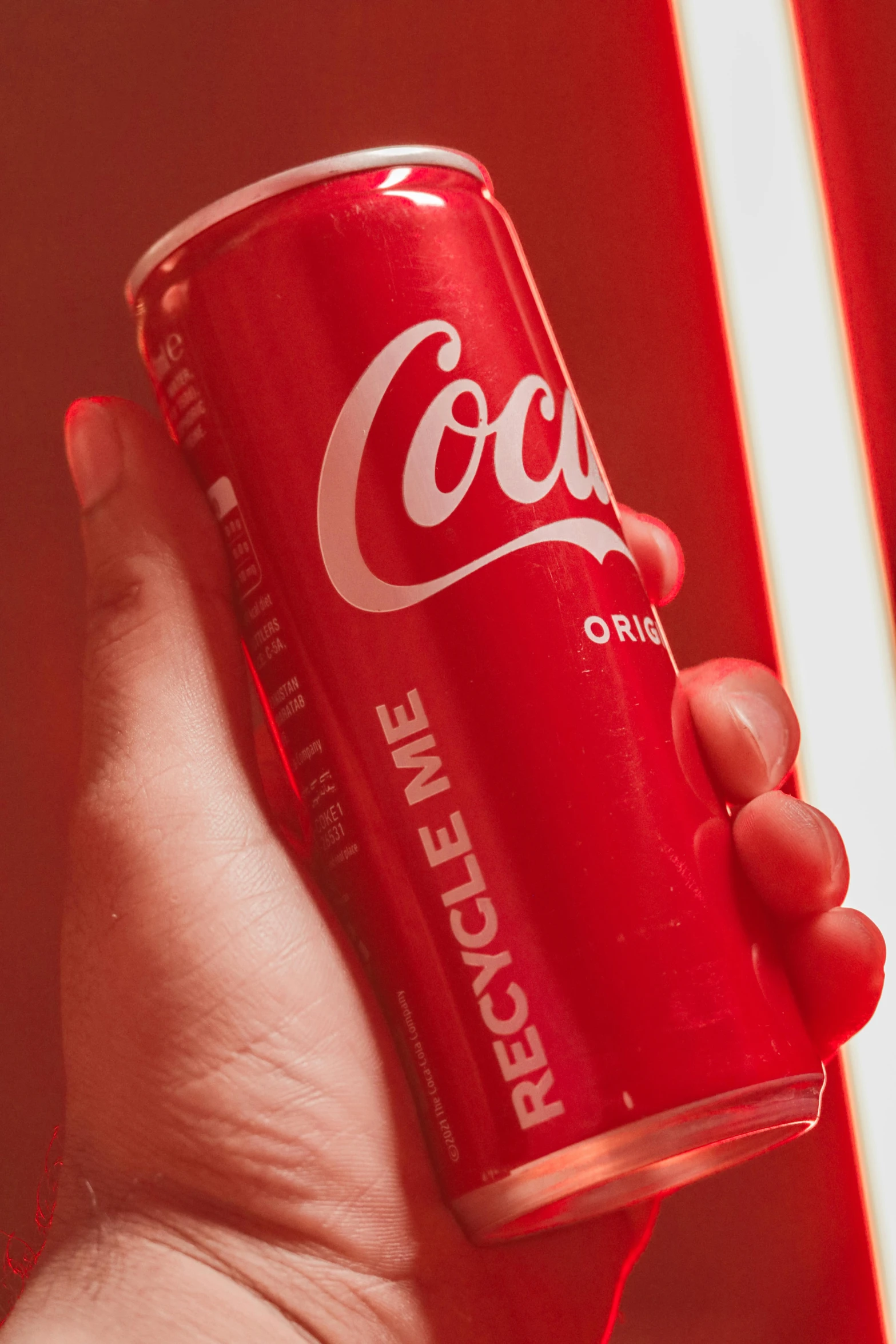 a hand is holding up a red coca cola can