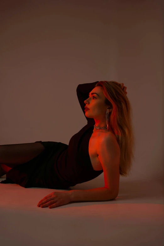 a woman in a black dress and hat laying down