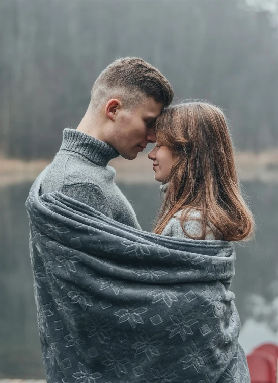 a couple wrapped in a blanket posing for the camera