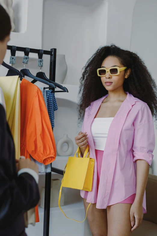 an african american woman stands next to clothing racks in a store