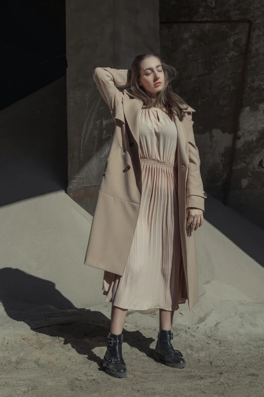 a young woman wearing a beige coat and black boots