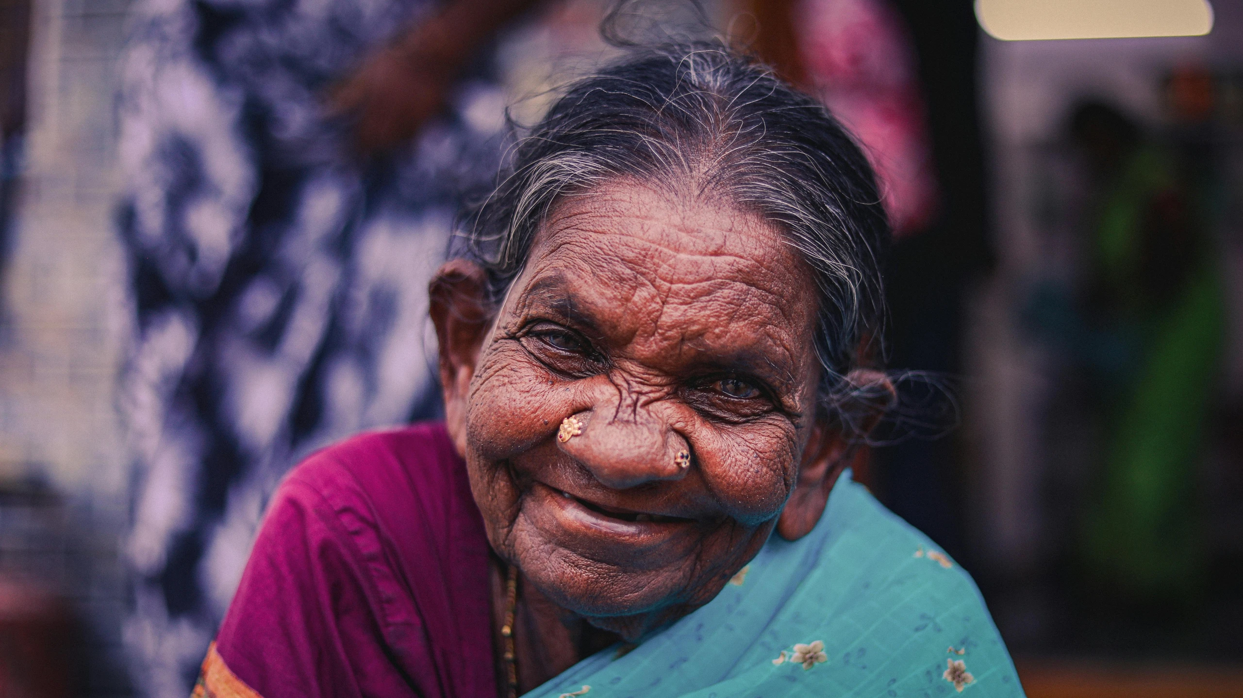 an elderly woman wearing a blue cloth and smiling