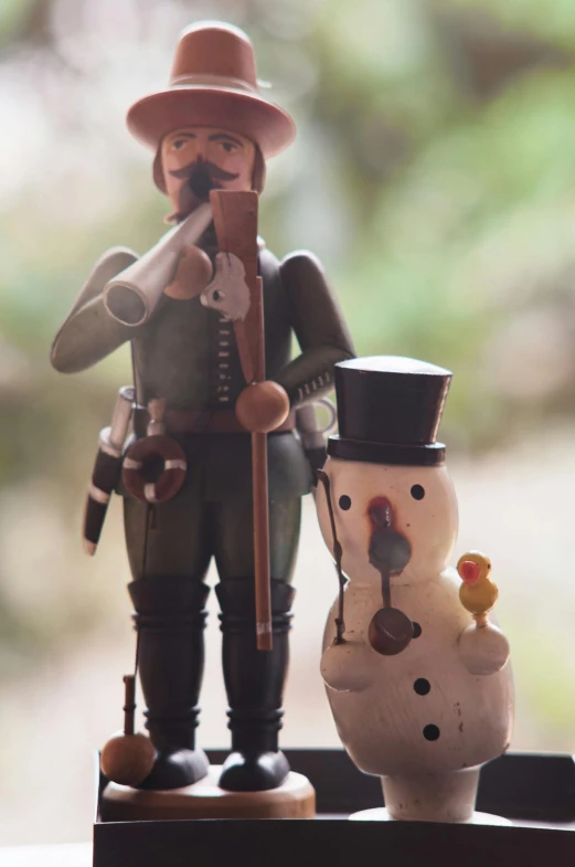 a wooden nuter standing beside an antique painted snowman