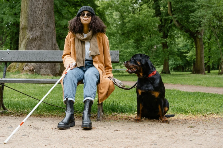 the woman is sitting on the park bench next to her black dog