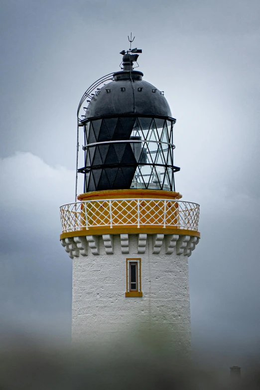 a white and yellow lighthouse with black roof and white base