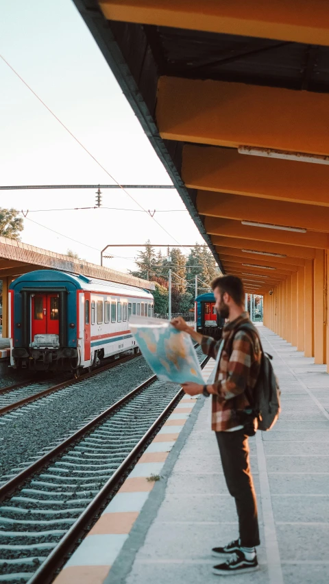 the man is looking at a map in a train station