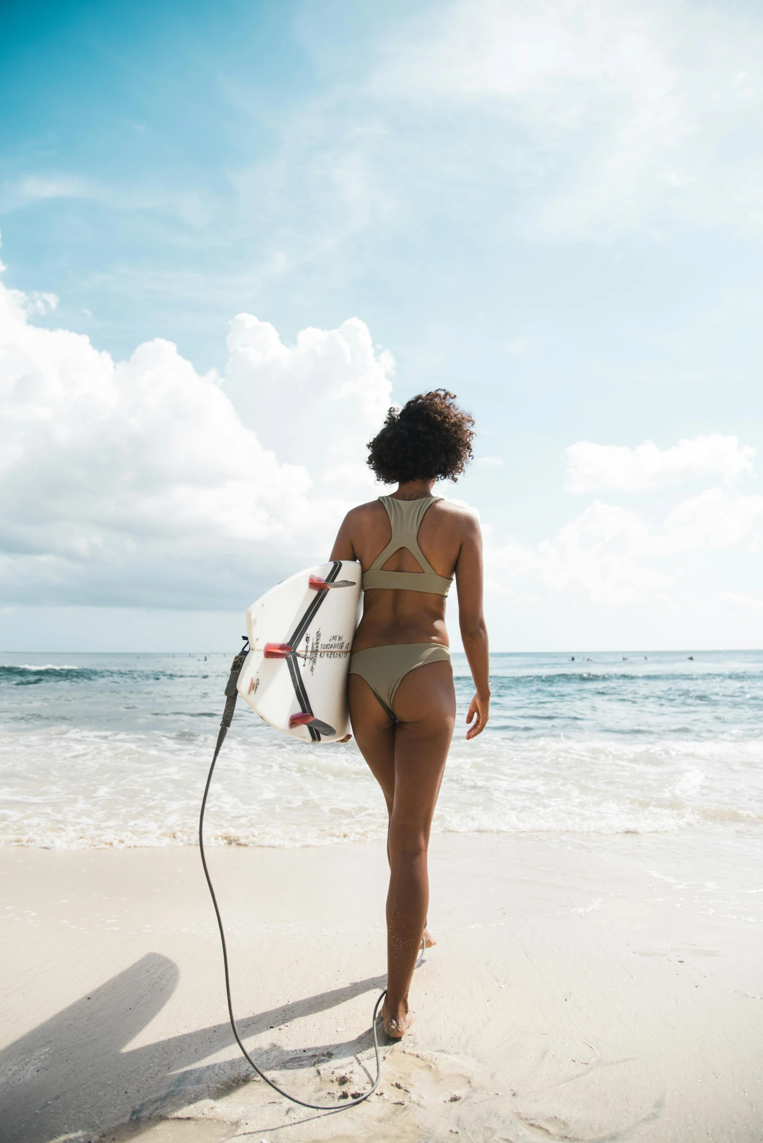 a woman in a bikini holding a surf board and walking down the beach