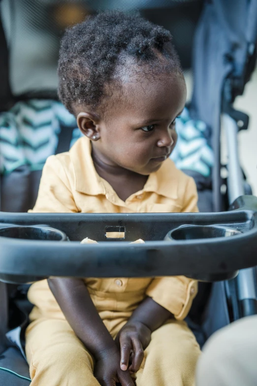 a little boy with short hair sitting in a stroller