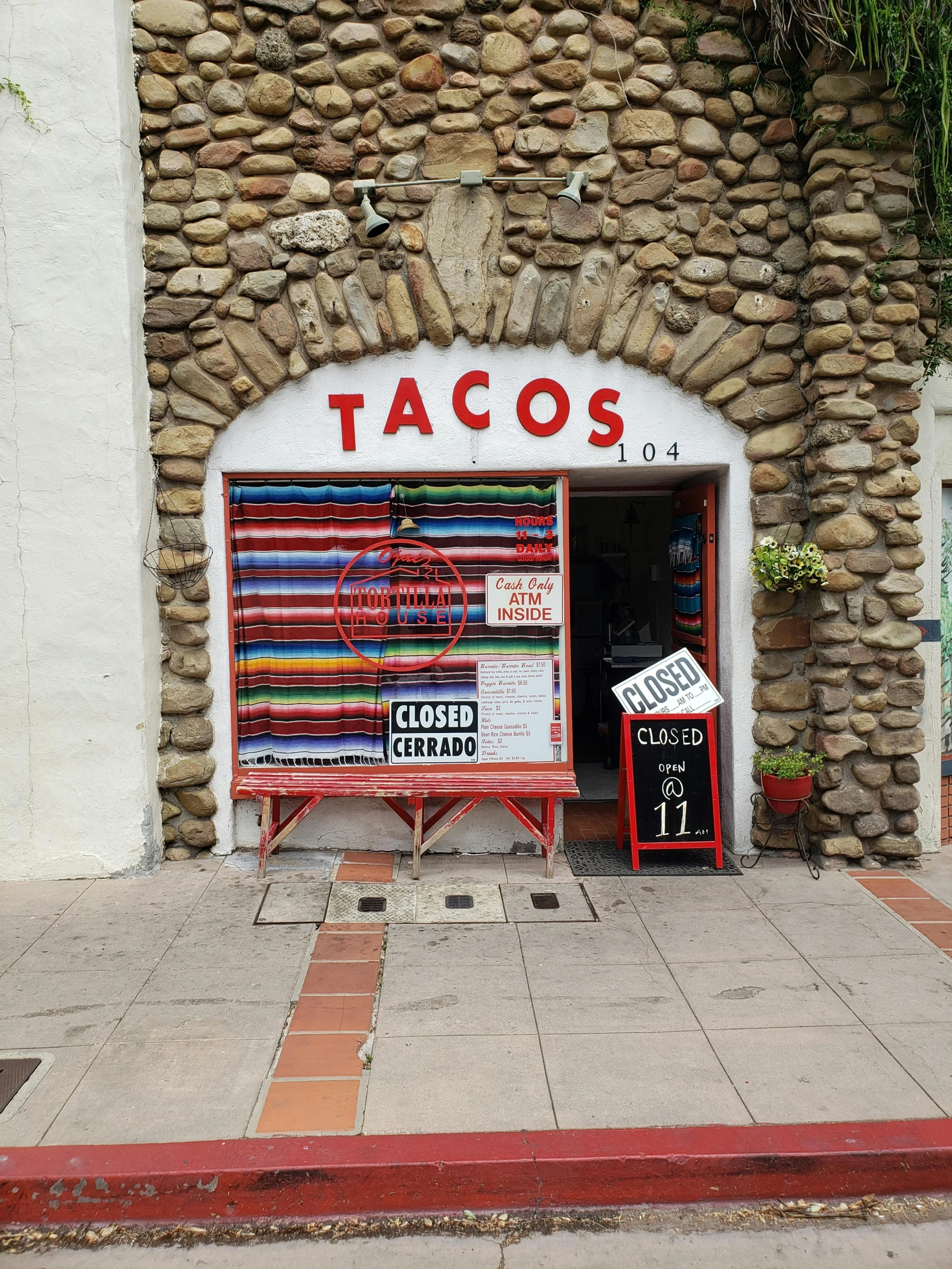 an image of a store front with signs and trash cans