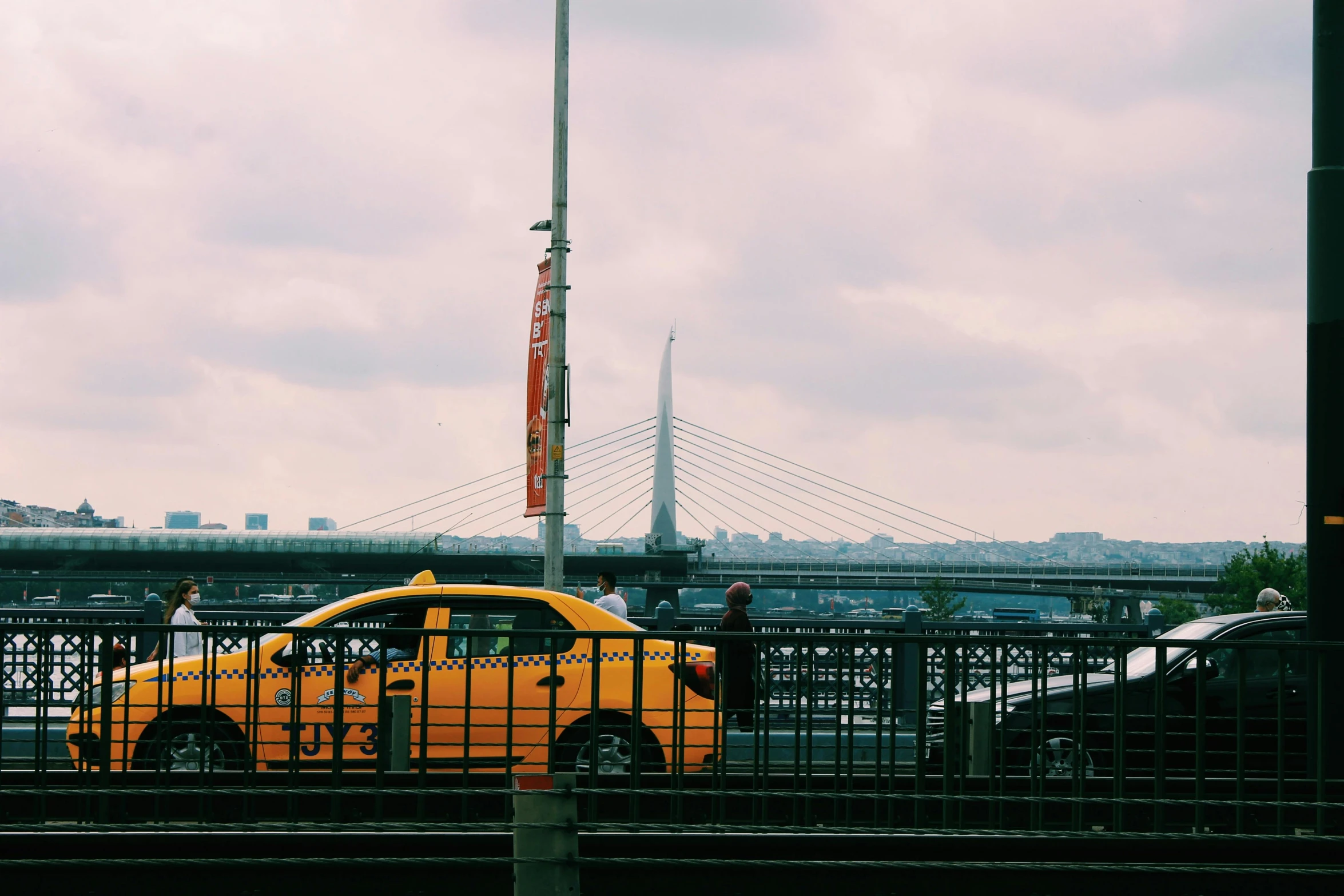 an yellow car behind a fence on top of a bridge