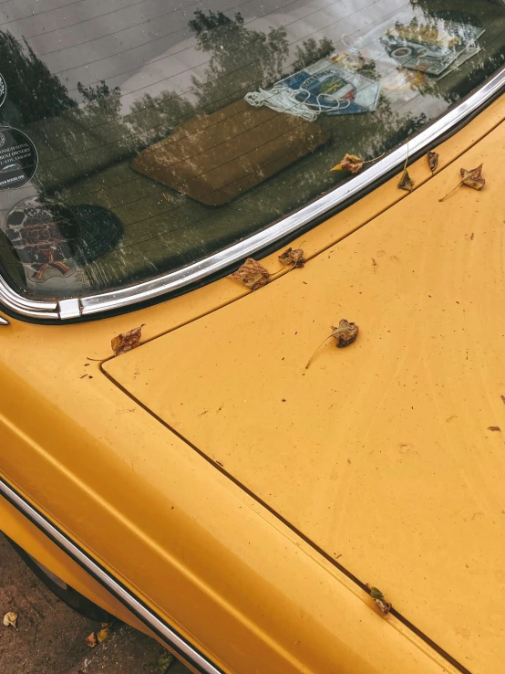 yellow car with rust on it sitting next to a wall