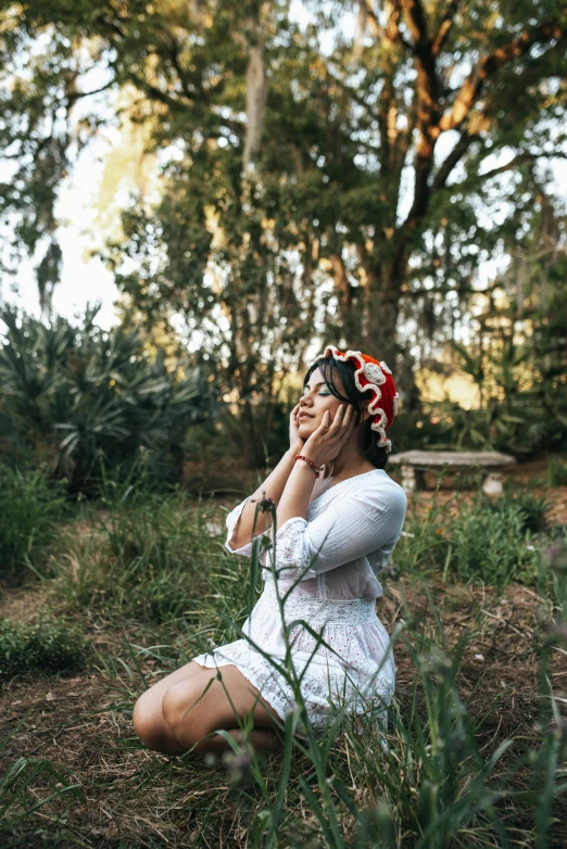 a woman sits in the grass and talks on the phone