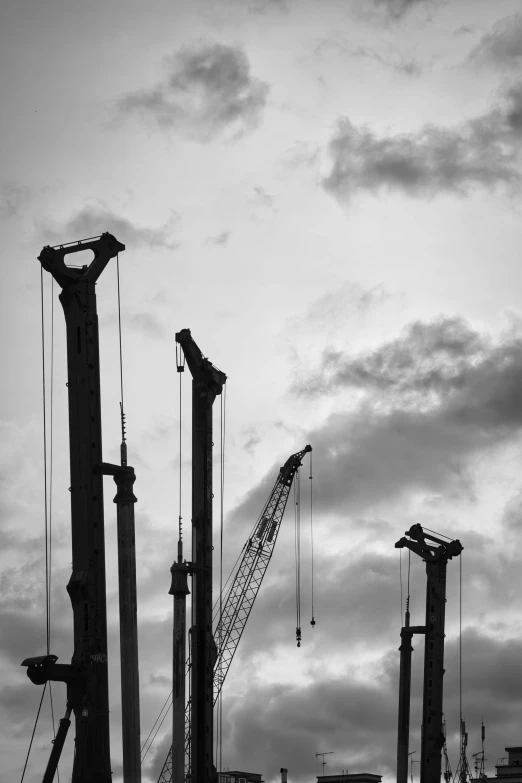 silhouetted crane cranes against a cloudy sky