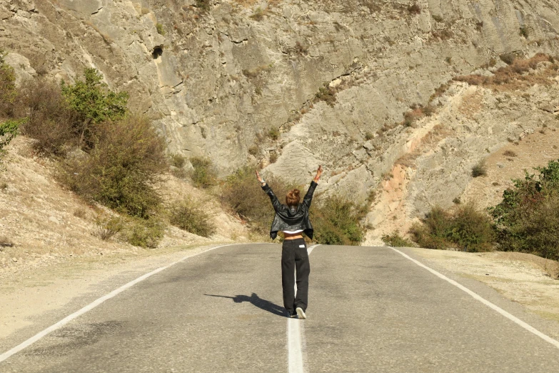 a woman is in the middle of a road waving