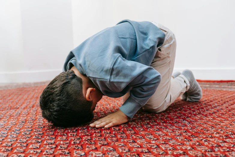 a man bends over on a rug to pick up soing