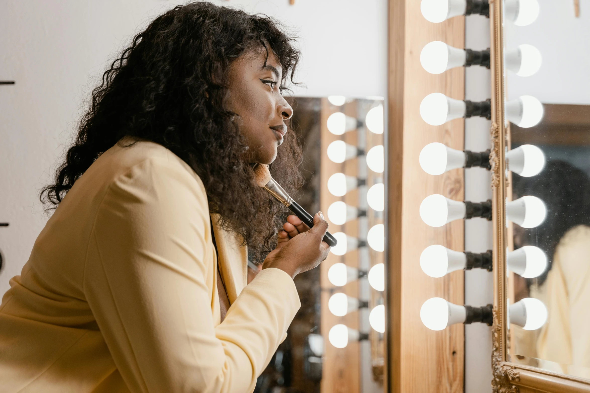 woman holding a pen in front of mirror with lights on it