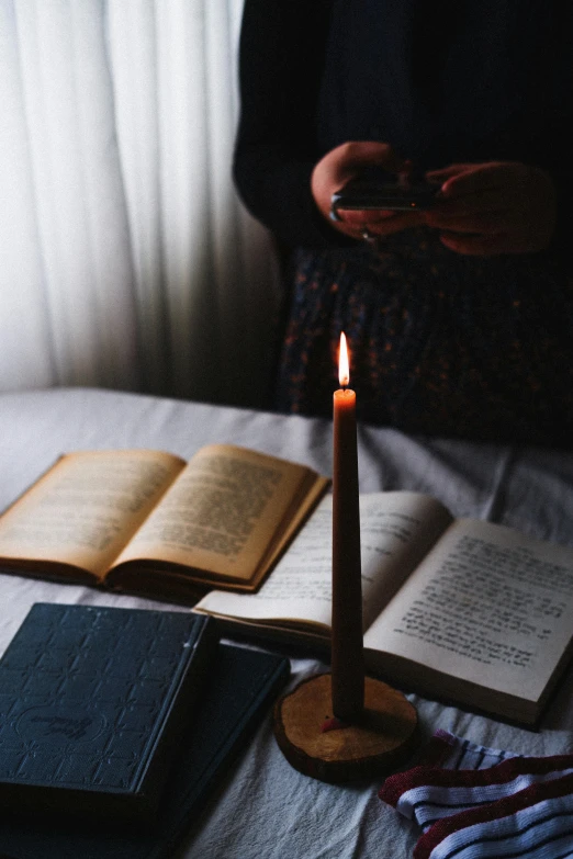 a candle and two books sitting on a bed