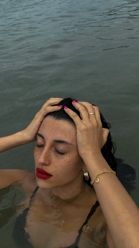 a young woman floating on top of water holding her head