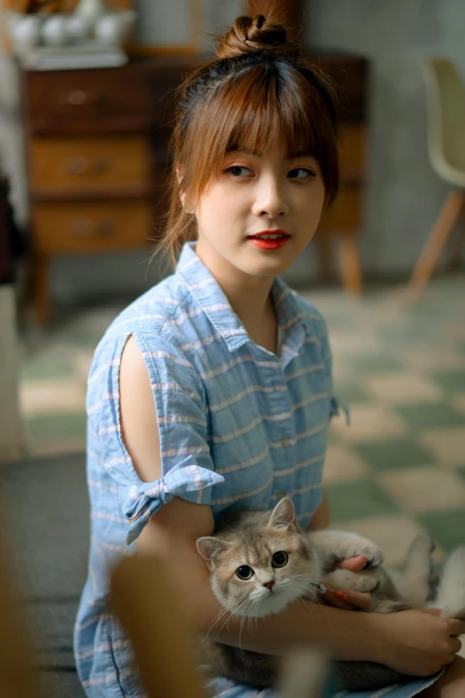 a woman in blue shirt holding cat sitting on chair