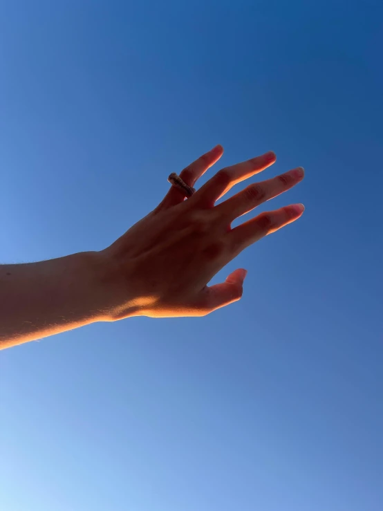 a persons hand reaching up into the sky