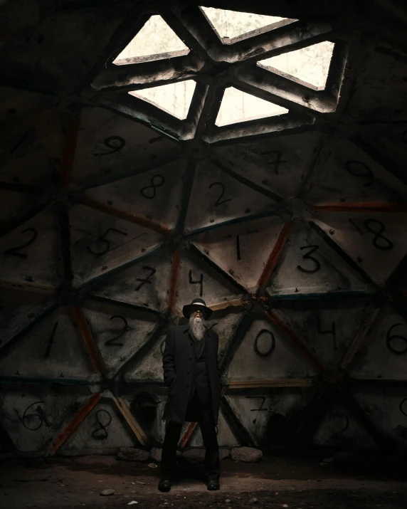 man standing in dark room with giant clock