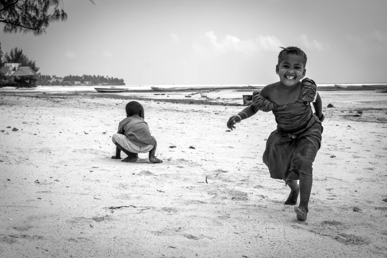 two children running across the sand on a beach