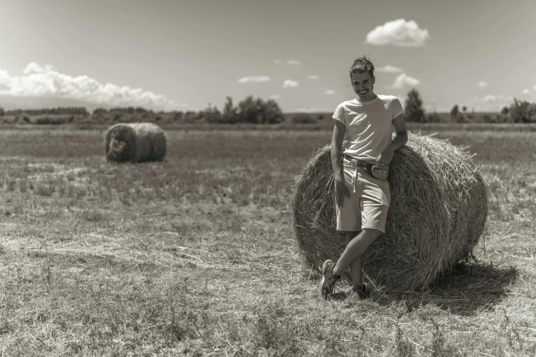 a man standing next to a bale of hay