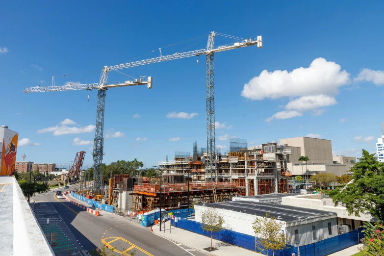 a view of a construction site with cranes, buildings and a car