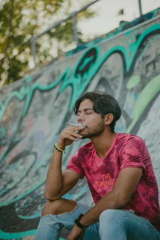 man sitting on a skateboard outside with his hand near his mouth